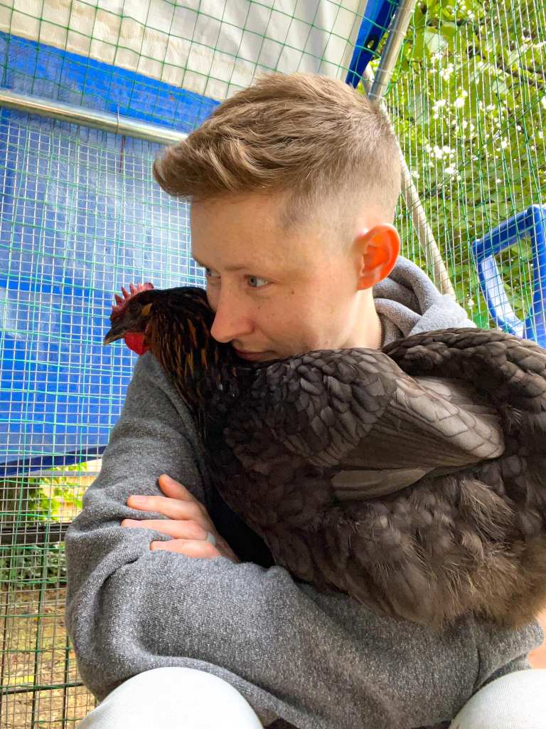 homesteader snuggling a pet chicken

